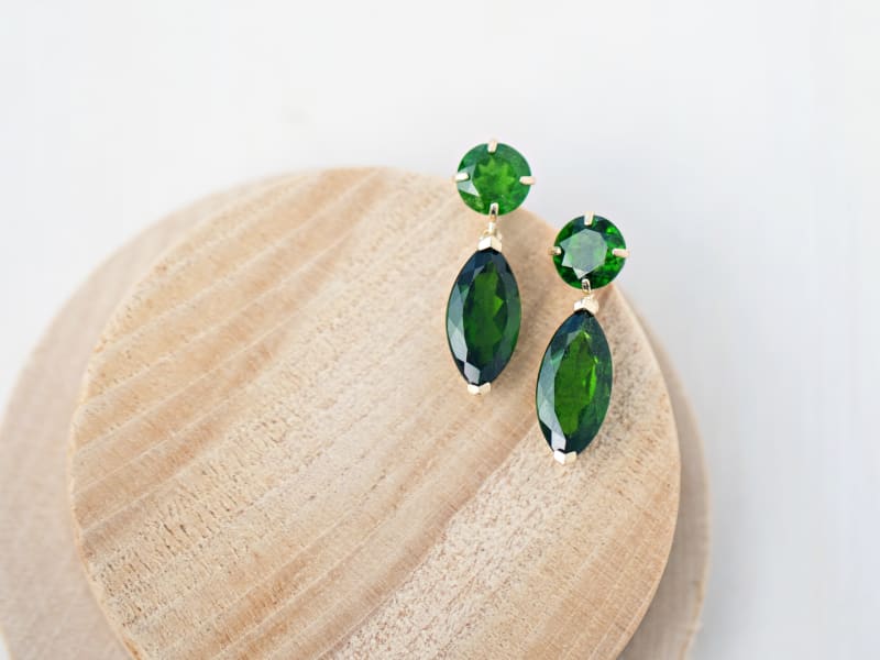 Russian green chrome diopside yellow gold earrings. The earrings are shot on a small round piece of wood.  