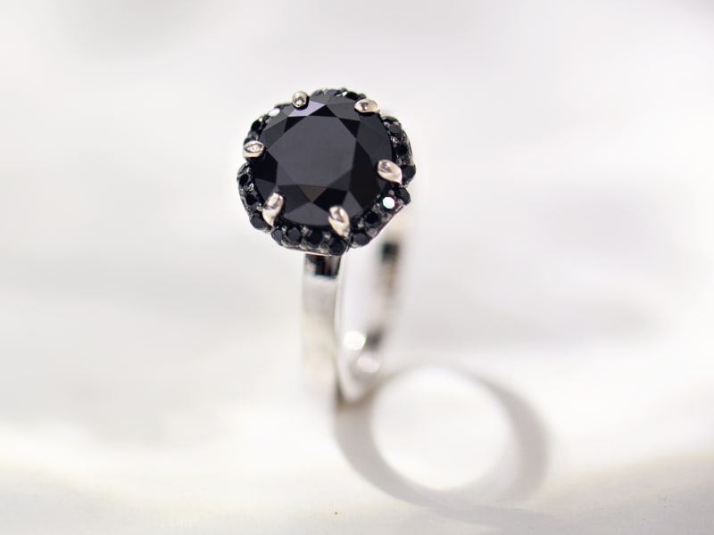 Close-up of a black spinel ring set in silver. The main stone is large and variegated and is surrounded by several smaller black spinels.  