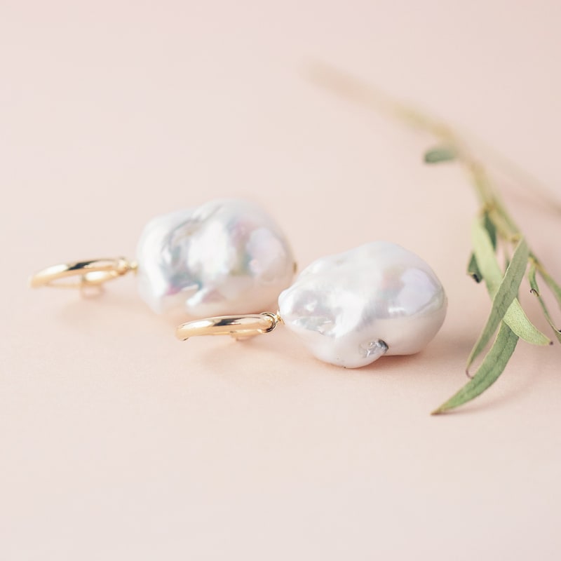 A pair of baroque pearl dangle earrings are shown. 