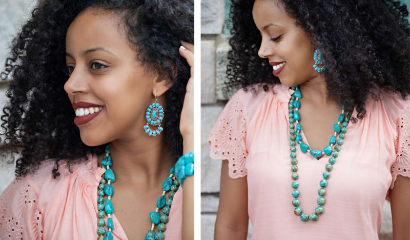 A dark curly haired woman wearing a pink shirt showing large turquoise earrings and wearing two turquoise beaded necklaces. 