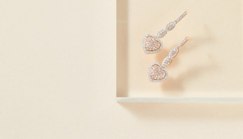 A pair of diamond heart shaped dangle earrings are shown. 