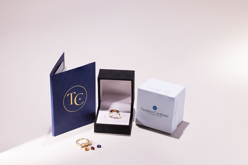 a timeless creation ring with assorted gems and packaging 