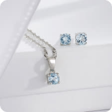 silver pendant and stud earrings with light blue birthstones