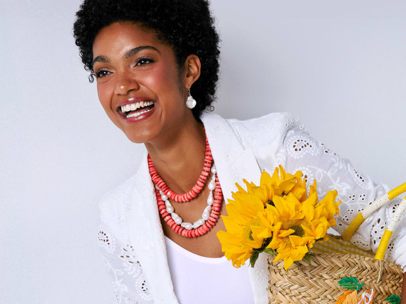 Woman wearing pearl jewelry and holding tote bag with sunflowers 
