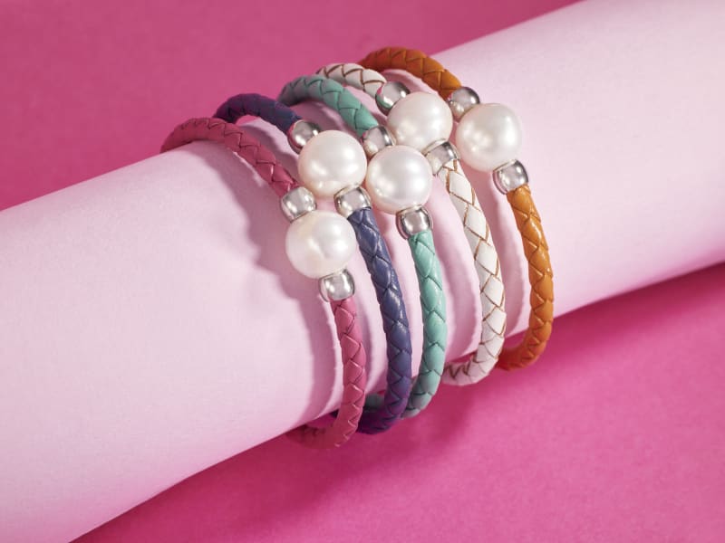 a stack of white pearl and different colored bracelets 