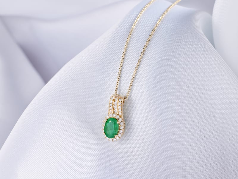 a gold, emerald pendant necklace adorned with small white gemstones 