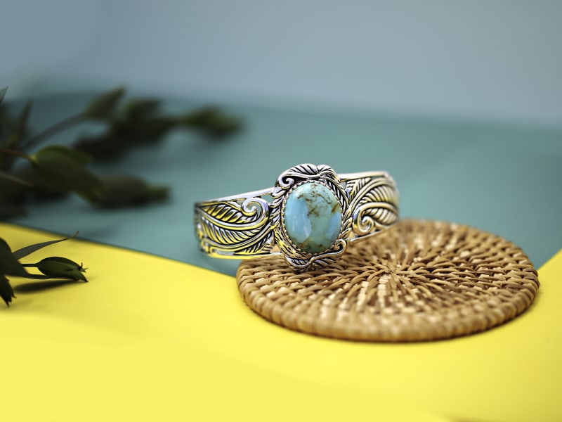A silver and turquoise ring against a yellow background 