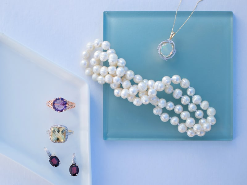 An assortment of birthstone jewelry against a blue background 