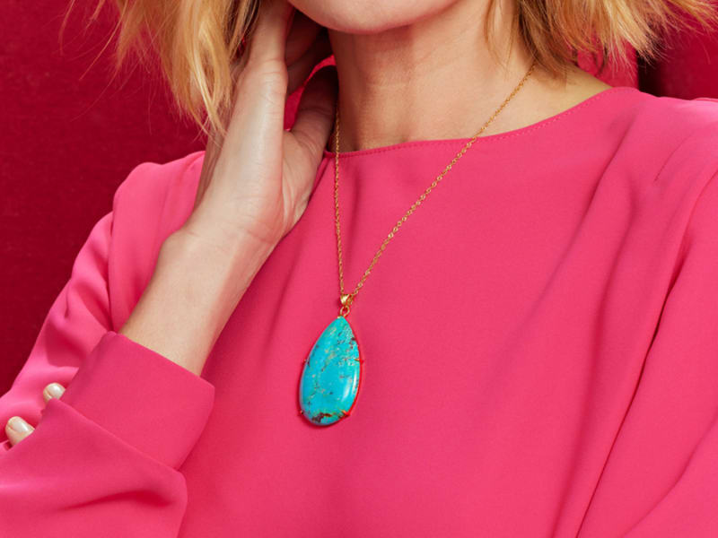 A model wears a blue Kingman Turquoise pendant with an 18k gold-over silver chain. 