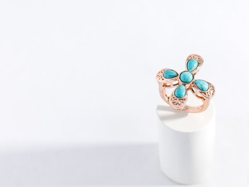 A cross-shaped copper and turquoise ring with filigree detail 