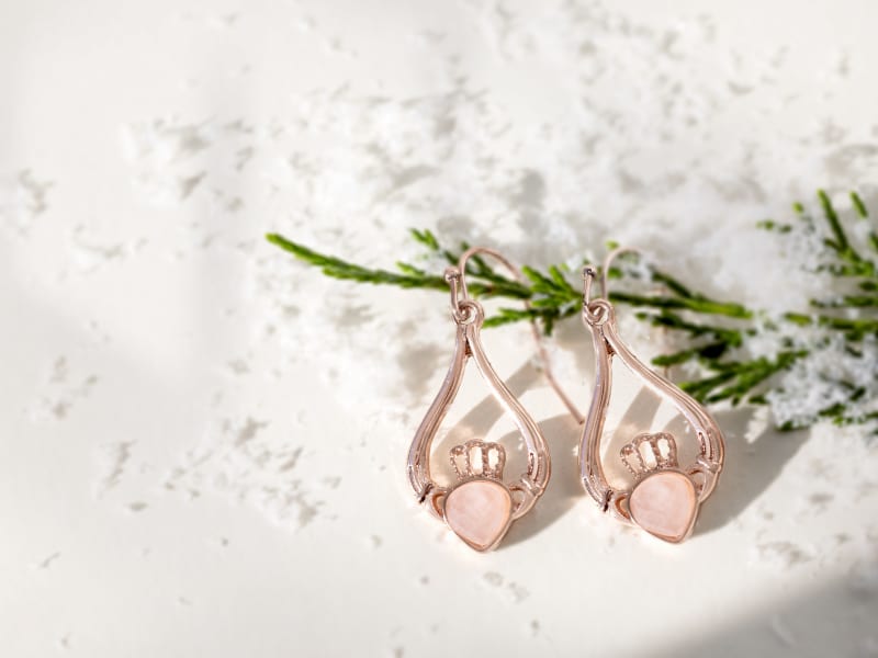 A pair of rose gold rose quartz claddagh earrings 
