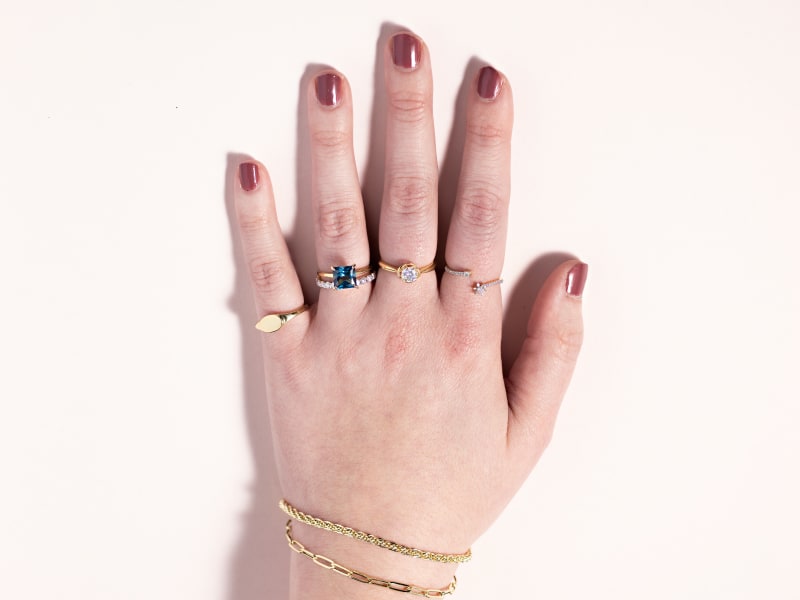 A woman wearing a gold ring on each finger and two gold bracelets 