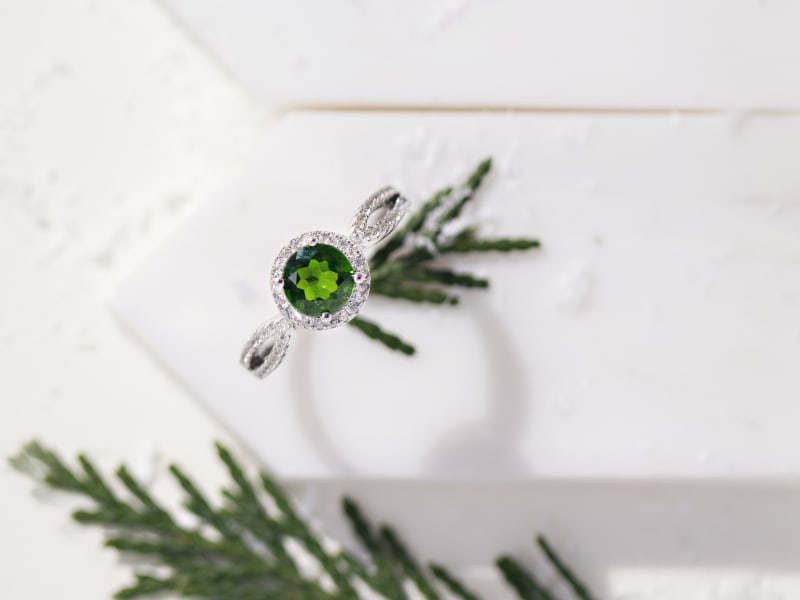 A silver chrome diopside ring sitting on a white tile 