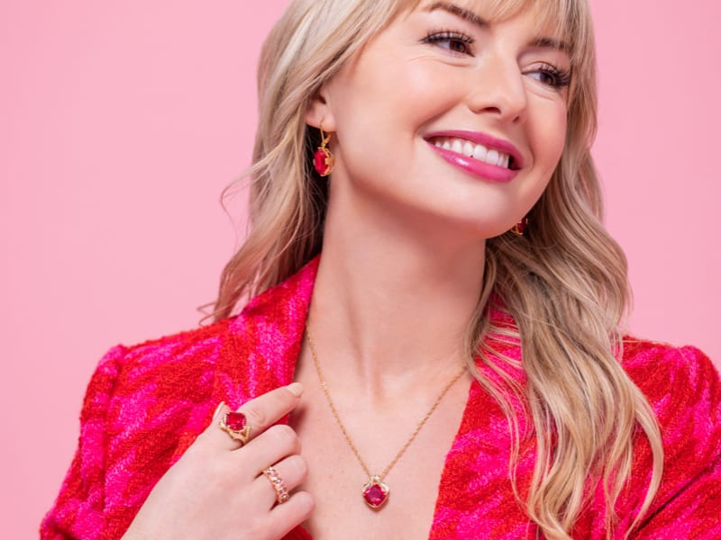 A woman wearing hot pink accessorized with a set of gold and hot pink jewelry 