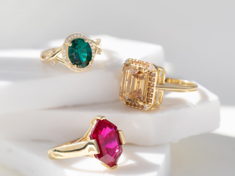 A trio of gold plated statement rings with different colored gemstones 