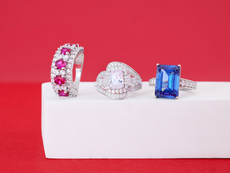 Three statement rings in red, white and blue sitting next to each other on a white stand 