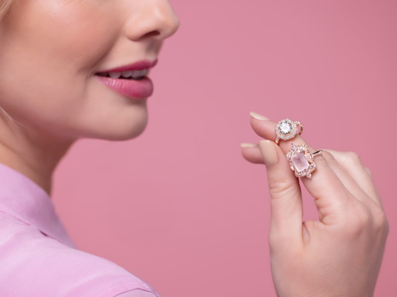 A woman holding two pink statement rings  
