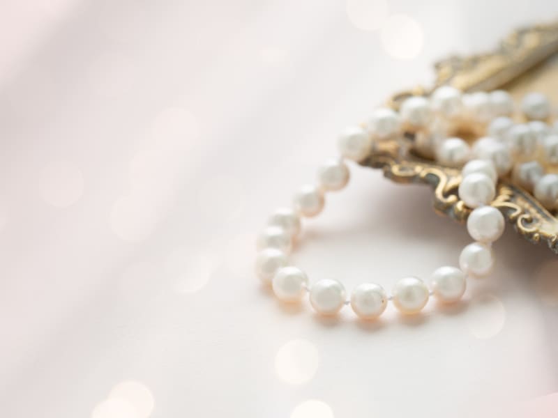 A strand of pearls sitting on a metal platter 