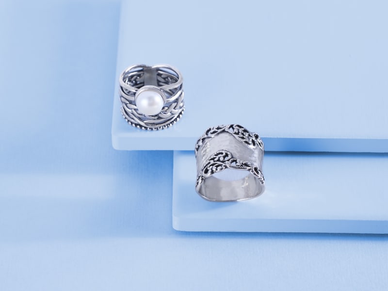 A pair of thick silver rings, one with a pearl gem 
