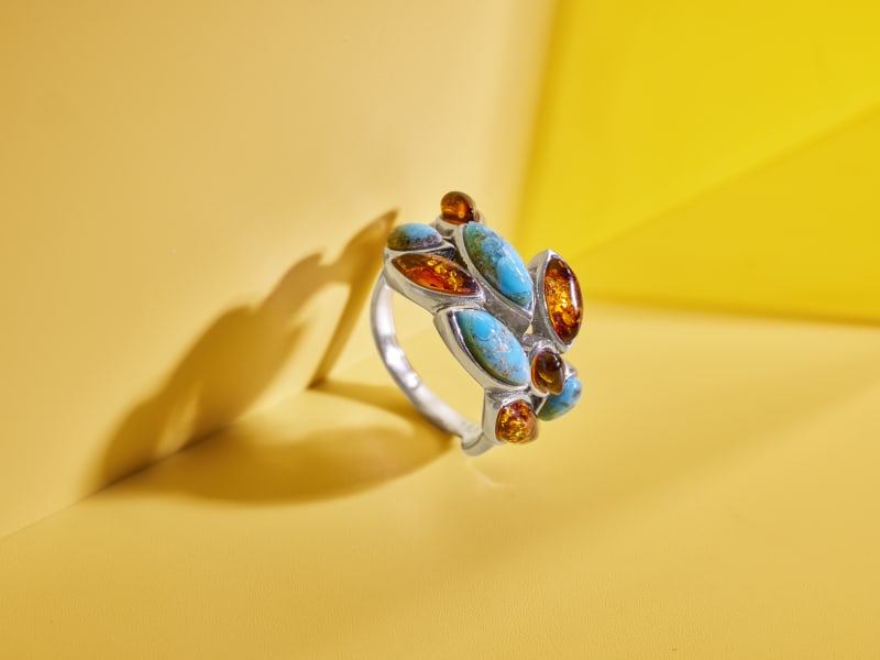 An amber and turquoise ring with leaf-shaped gems and a silver band 