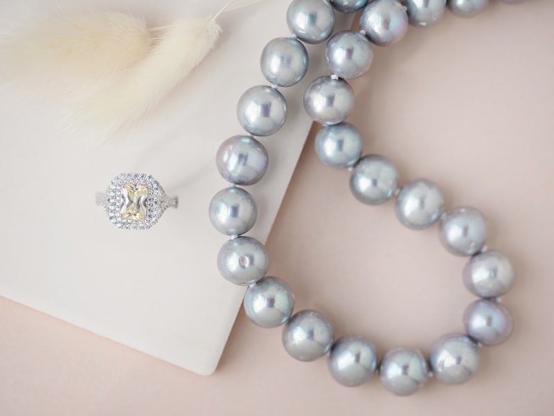 A grey pearl necklace and a silver and yellow ring 