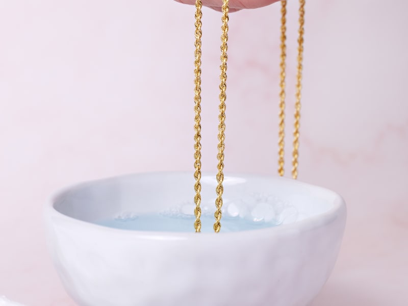 Gold jewelry soaking in warm soapy water 