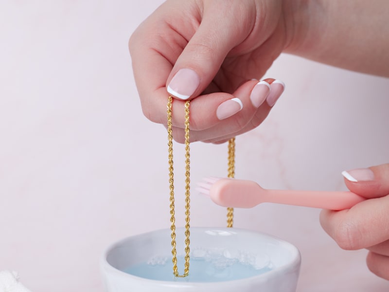 Gold chain being gently scrubbed with brush 