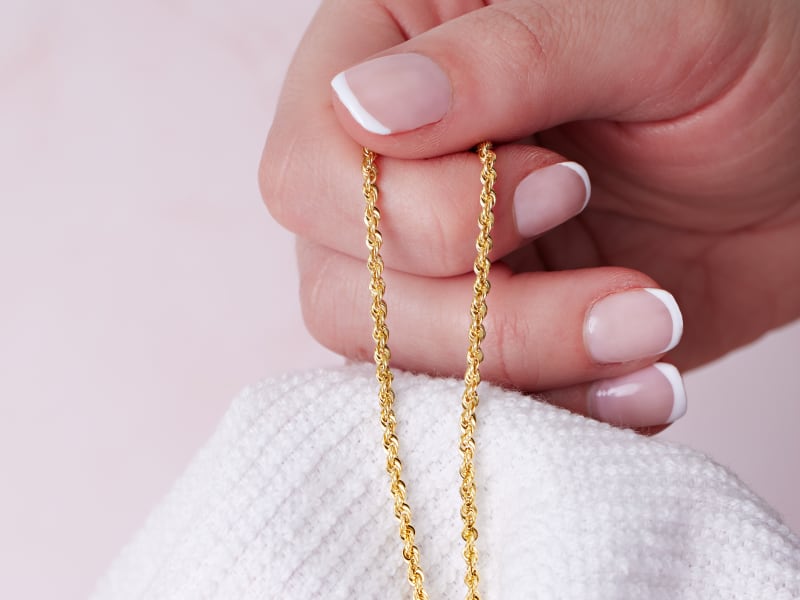 Gold chain being patted dry with a soft cloth 