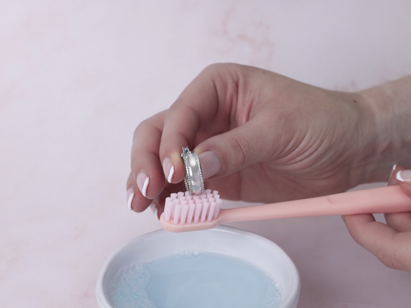 gently brushing jewelry with soft-bristled brush 