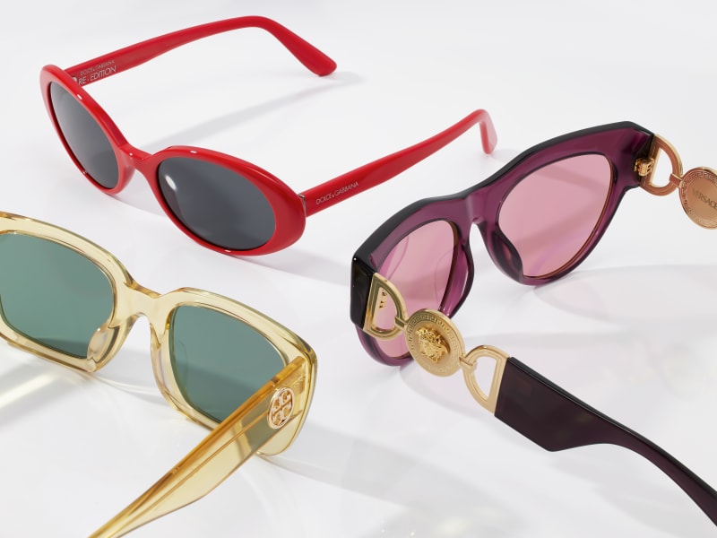 Three designer brand sunglasses: one red pair, one purple, and one yellow pair