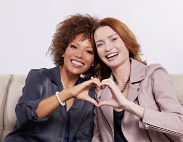 two women making a heart with their hands 