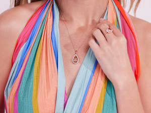 A woman wears a morganite and rose gold necklace and ring. 